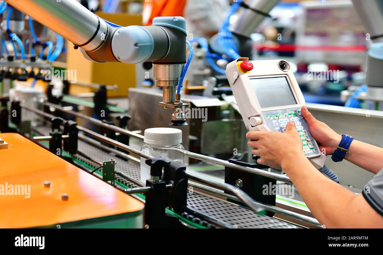 Techniker überprüfen und Steuerung Automatisierung Roboter Arme arrangiert Glas Flasche Wasser auf der automatischen Maschinen und Anlagen in der Produktion im Werk Stockfoto