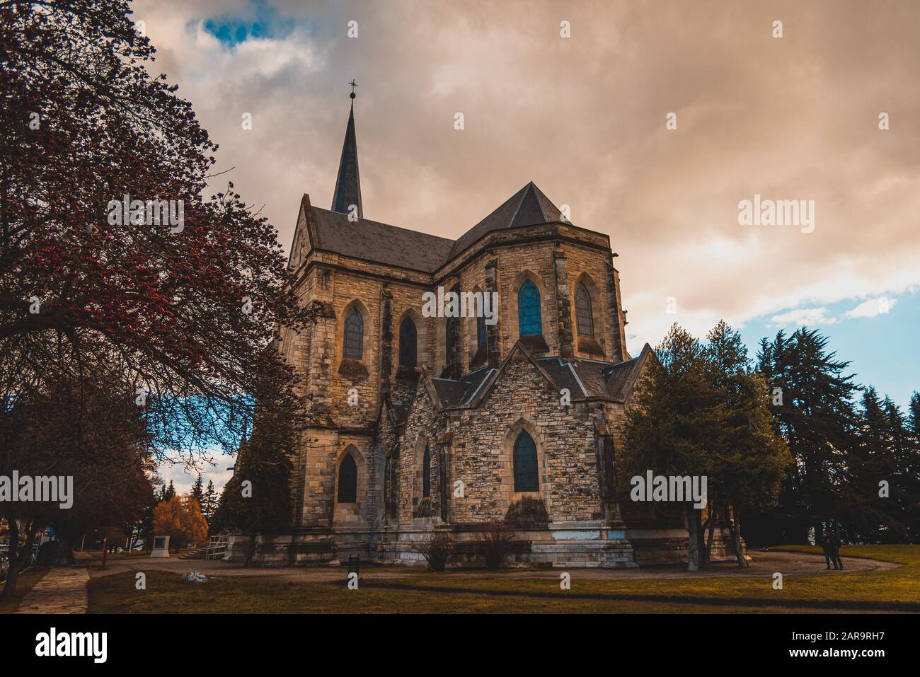 BARILOCHE, ARGENTINIEN, 18. JUNI 2019: Farbenfroher Pfad mit roten Bäumen neben der Kathedrale Nuestra Senora del Nahuel Huapi. Stockfoto