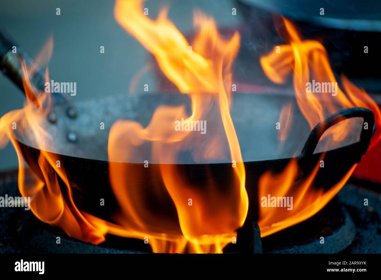 Koch kocht mit Feuer in Bratpfanne auf der Straße Stockfoto