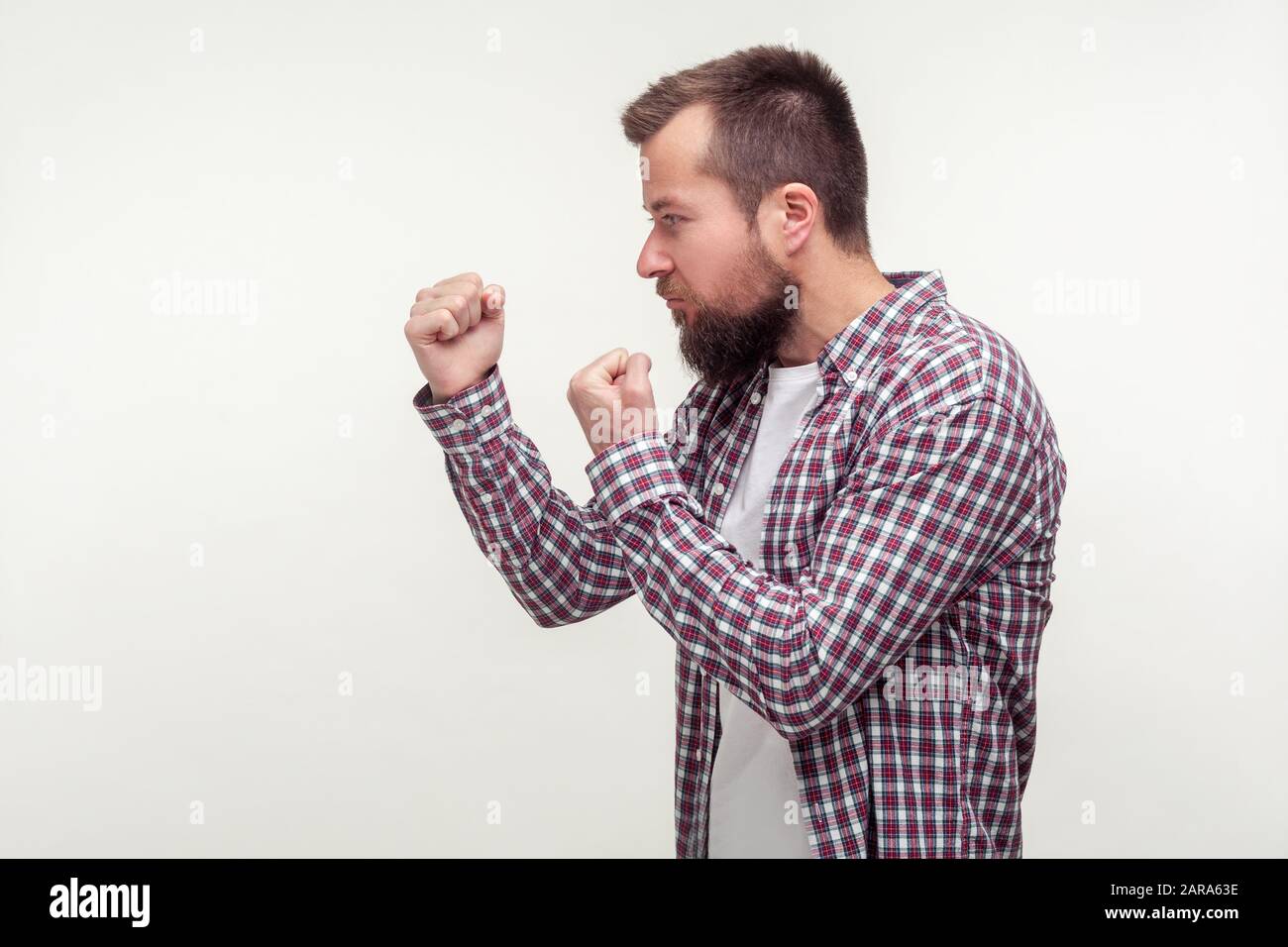 Lasst uns kämpfen! Seitenansicht des aggressiven bärtigen Mannes in legeren Kragenhemden mit erhobenen Fäusten stehend, druckbereit, leerer Platz für Anzeigentext, Kopierraum Stockfoto