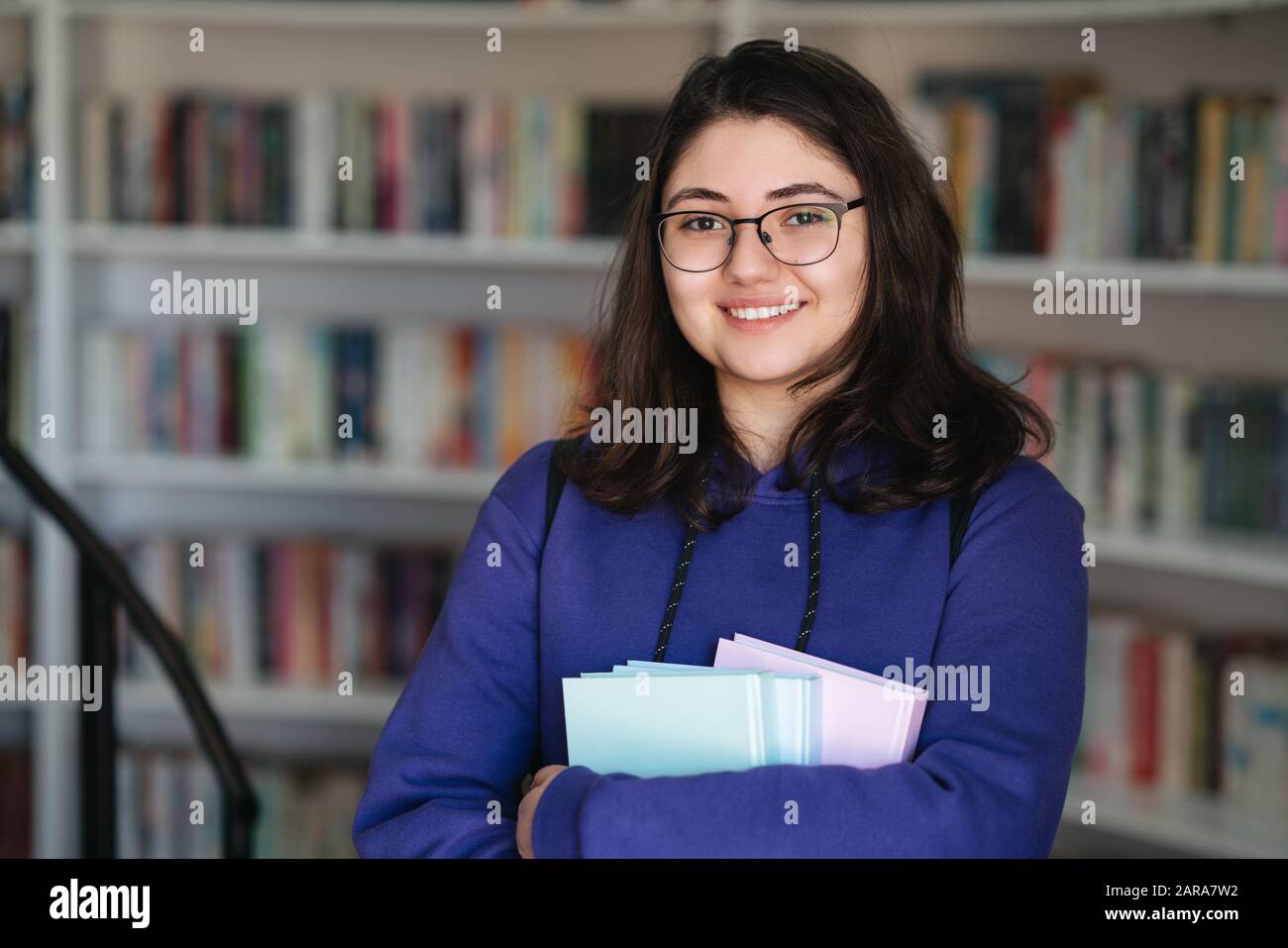 Intellektuelles Teenager-Mädchen wählt Bücher aus und wählt sie aus einer Bibliothek oder einem Buchladen Stockfoto