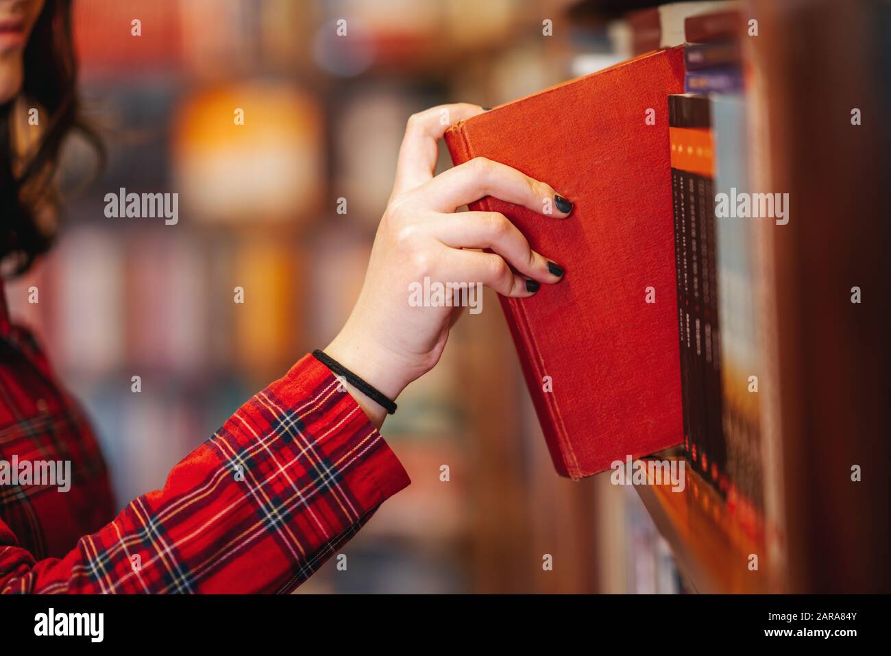 Intellektuelles Teenager-Mädchen wählt Bücher aus und wählt sie aus einer Bibliothek oder einem Buchladen Stockfoto