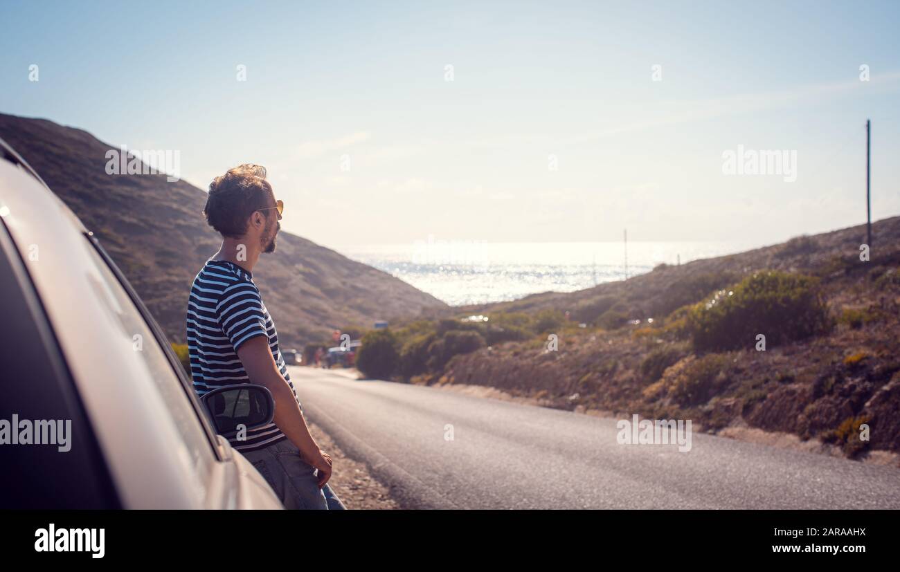 Mann auf einer Fahrt mit dem Auto, der auf dem Meer liegt Stockfoto
