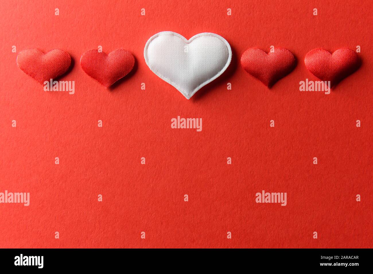 Rot-weiße Textilherzen auf rotem Papier. Valentinstag Hintergrund, kreative Textur und Liebeskonzept Stockfoto