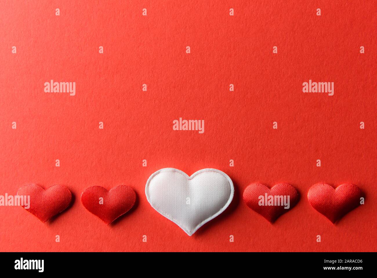Rot-weiße Textilherzen auf rotem Papier. Valentinstag Hintergrund, kreative Textur und Liebeskonzept Stockfoto