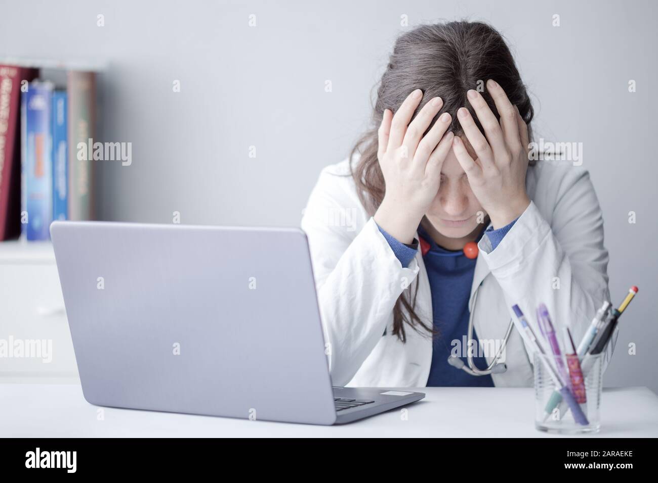 Müde Junge Frau Doktor, Die Mit einem Laptop in einer Klinik arbeitet Stockfoto