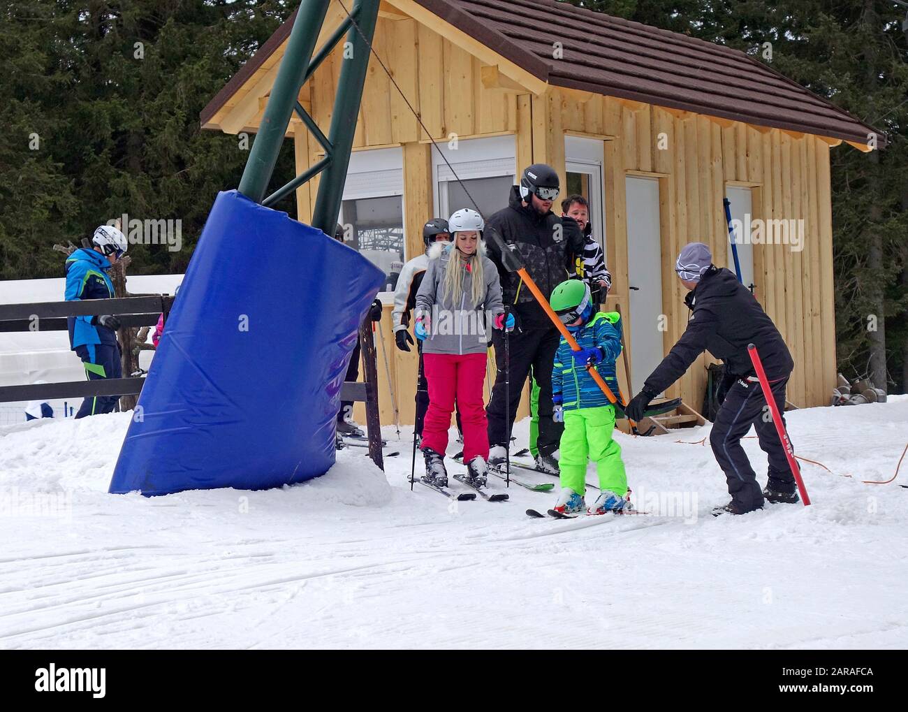 Ein junger Skifahrer erhält Hilfe von einem Begleiter auf dem T-Bar Surface Skilift. Skigebiet Rogla, Slowenien. Stockfoto