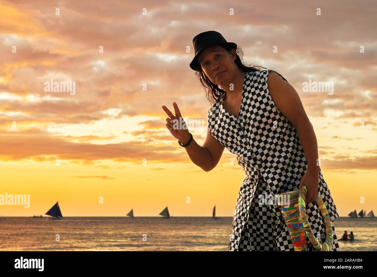 Boracay, Aklan, Philippinen - 1. Januar 2020: Mann auf Stelzen, der bei Sonnenuntergang am weißen Strand jongliert und ein Friedenszeichen für die Kamera gibt Stockfoto
