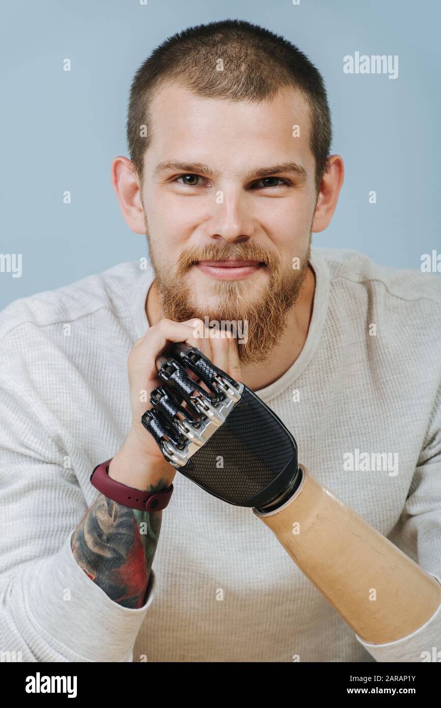 Porträt eines glücklichen Mannes mit prothetischem Bionikarm über blauem Hintergrund Stockfoto