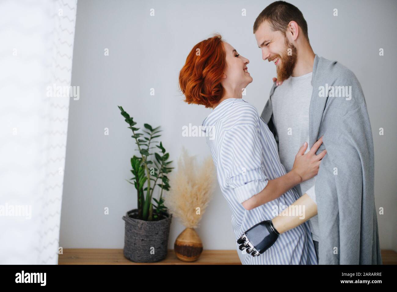 Glückliches Ehepaar verliebt sich zu Hause, steht dicht, schaut einander an Stockfoto