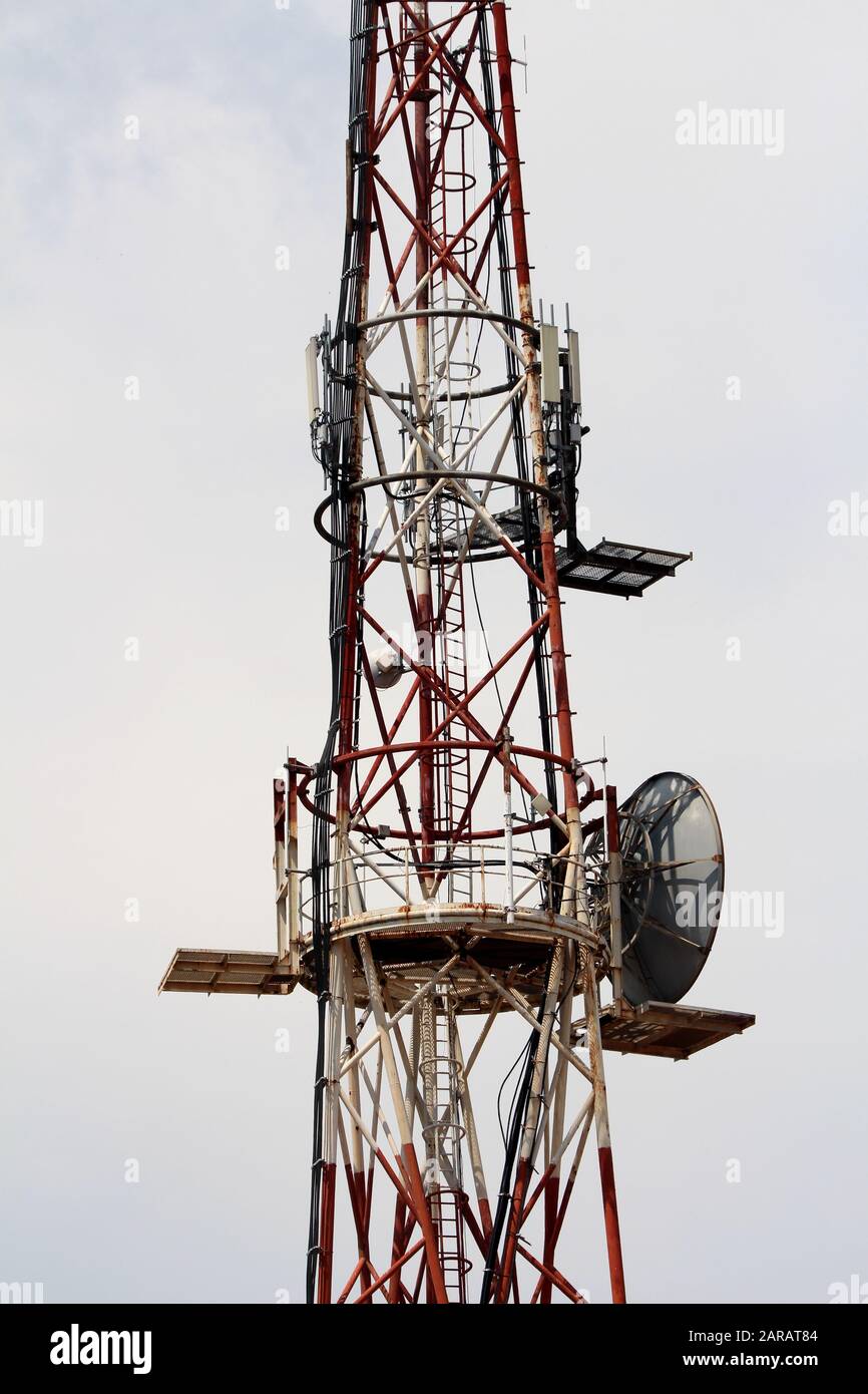 Mittlerer Teil des hohen roten und weißen Antennentowers mit mehreren Antennen und Sendern auf dem Bürogebäude am klaren Himmel Stockfoto