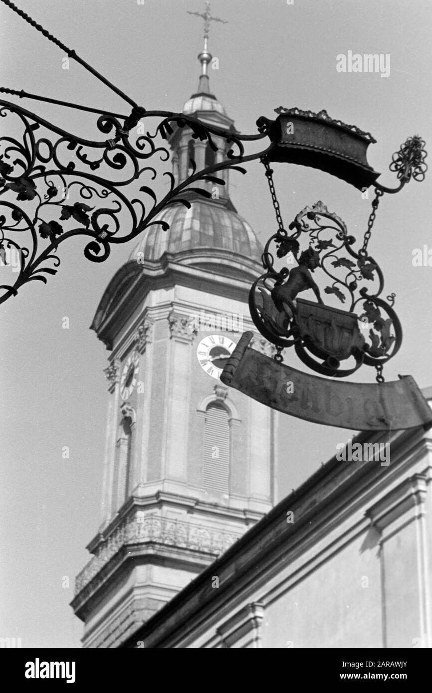 Kneipenschild Höllbräu mit dem Turm der St. Oswald-Kirche, 1957. Kneipschild Höllbräu mit St. Oswalds Kirchturm, 1957. Stockfoto