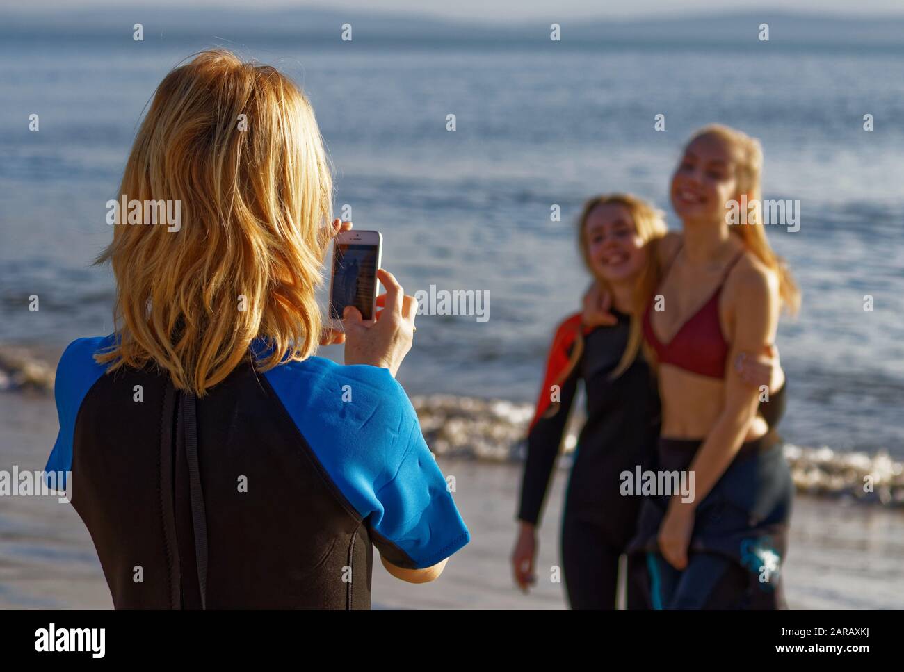 Stolze Mutter fotografieren ihre Töchter nach dem Schwimmen im Meer am Neujahrstag Stockfoto