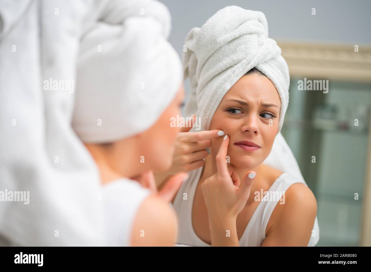 Junge Frau drückt Pickel im Bad. Stockfoto