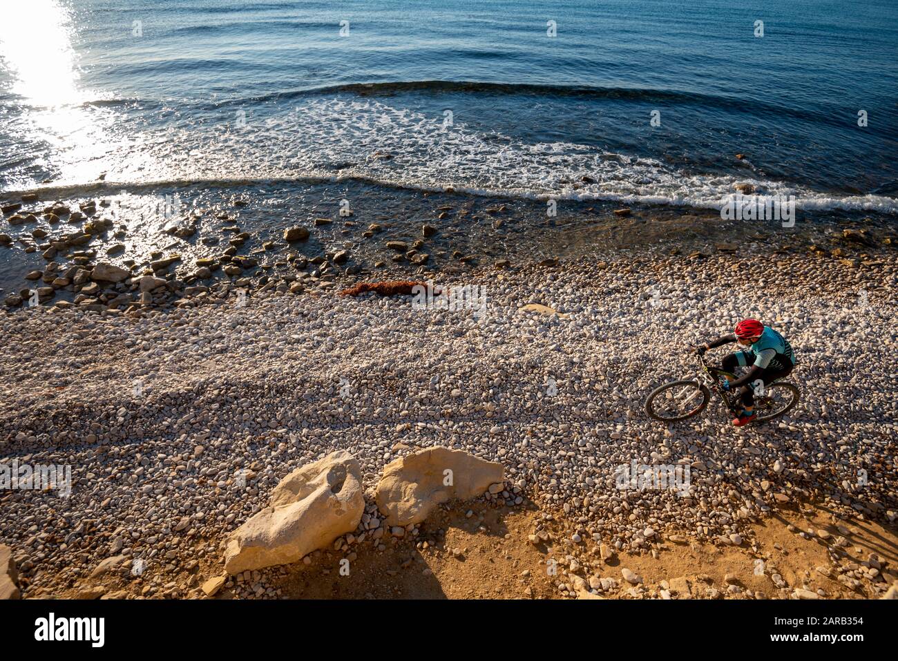 Mountainbiker, die sich auf dem Küstenstrand bewegen; El Charco Beach; Villajoyosa Village; Provinz Alicante; Spanien Stockfoto