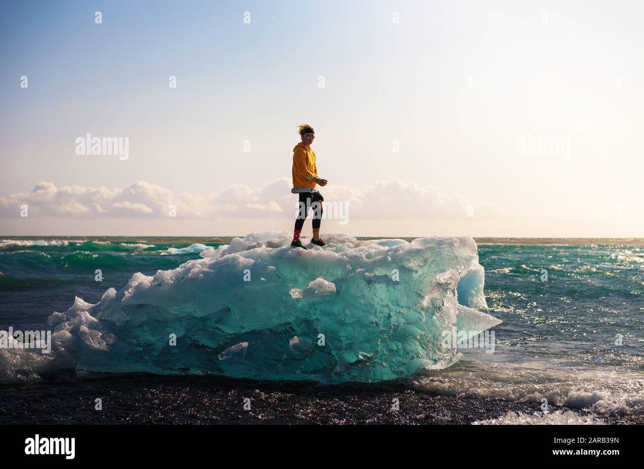 Tourist steht auf einem Eisberg am Diamond Beach, Island Stockfoto