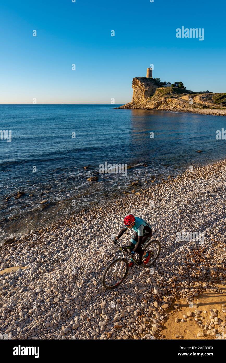 Mountainbiker, die sich auf dem Küstenstrand bewegen; El Charco Beach; Villajoyosa Village; Provinz Alicante; Spanien Stockfoto