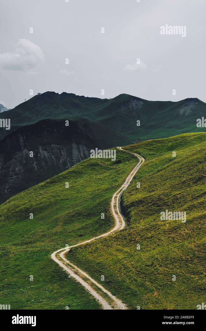 Ein Fußweg durchschneidet die grüne Ackerlandlandschaft von Stoos, Morschach, Schwyz, Schweiz EU - Schweizer Alpen Sommerberglandschaft Stockfoto