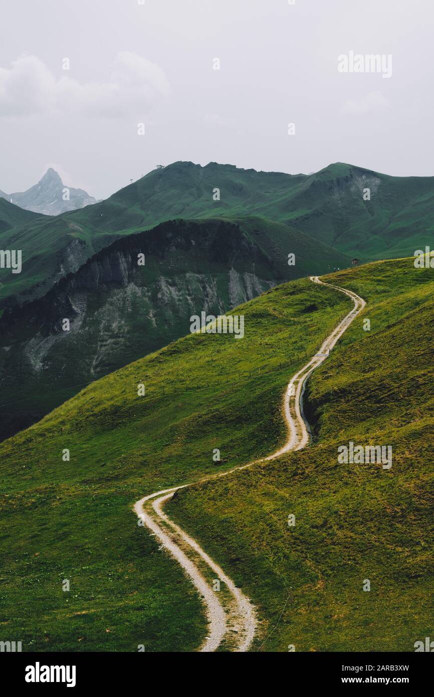 Ein Fußweg durchschneidet die grüne Ackerlandlandschaft von Stoos, Morschach, Schwyz, Schweiz EU - Schweizer Alpen Sommerberglandschaft Stockfoto