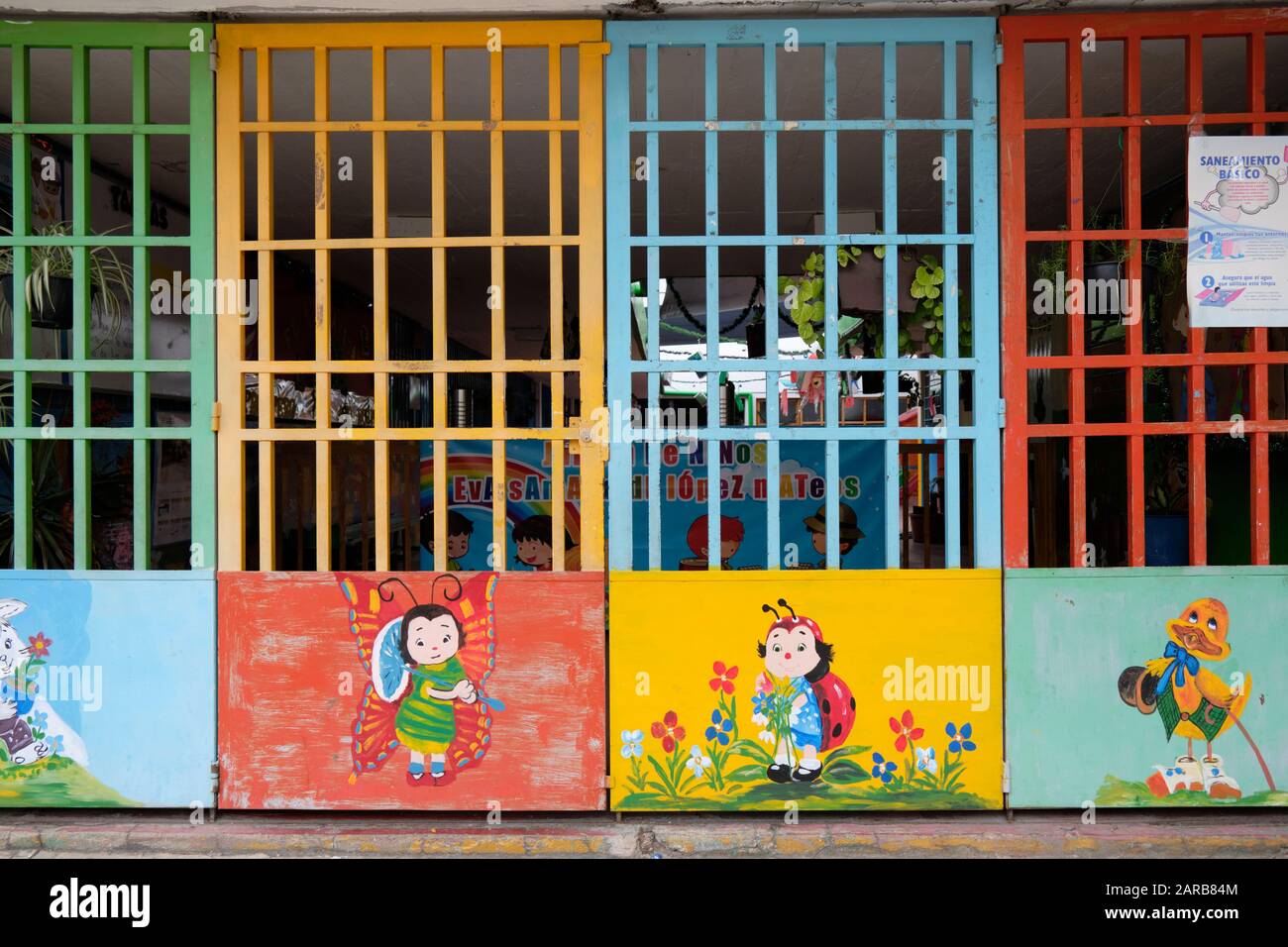 Bunt bemalte Tür am Eingang eines mexikanischen Kindergartens. Die Türen sind mit kindlichen Bildern von Insekten und Tieren ausgestattet. Oaxaca, Mexiko Stockfoto