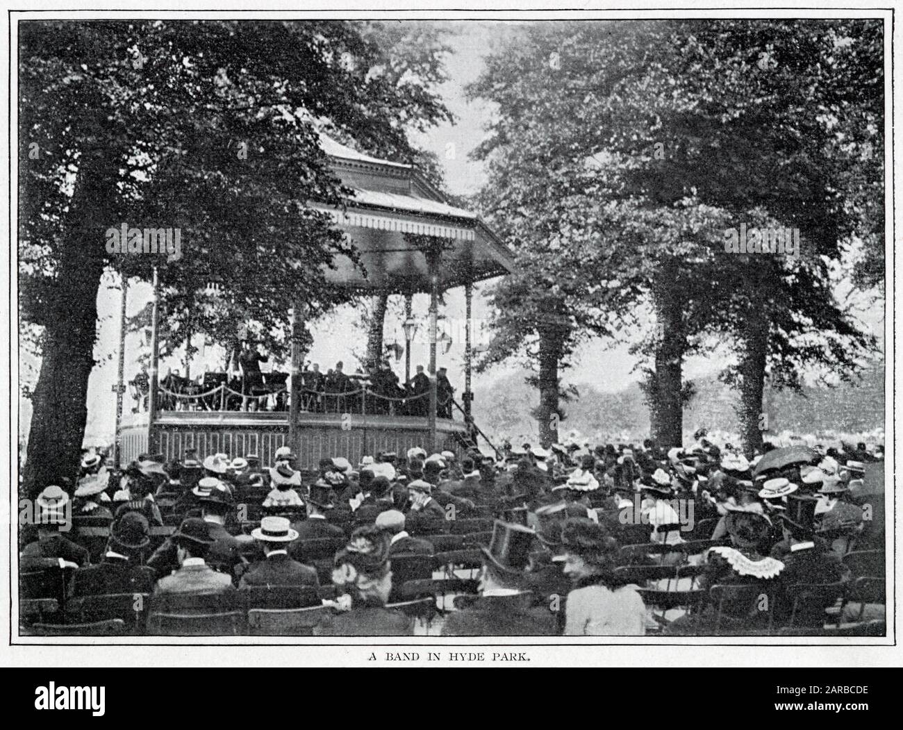 Viktorianische Männer und Frauen sitzen an einem Sommertag vor dem Bandstand im Hyde Park, London. Datum: 1900 Stockfoto