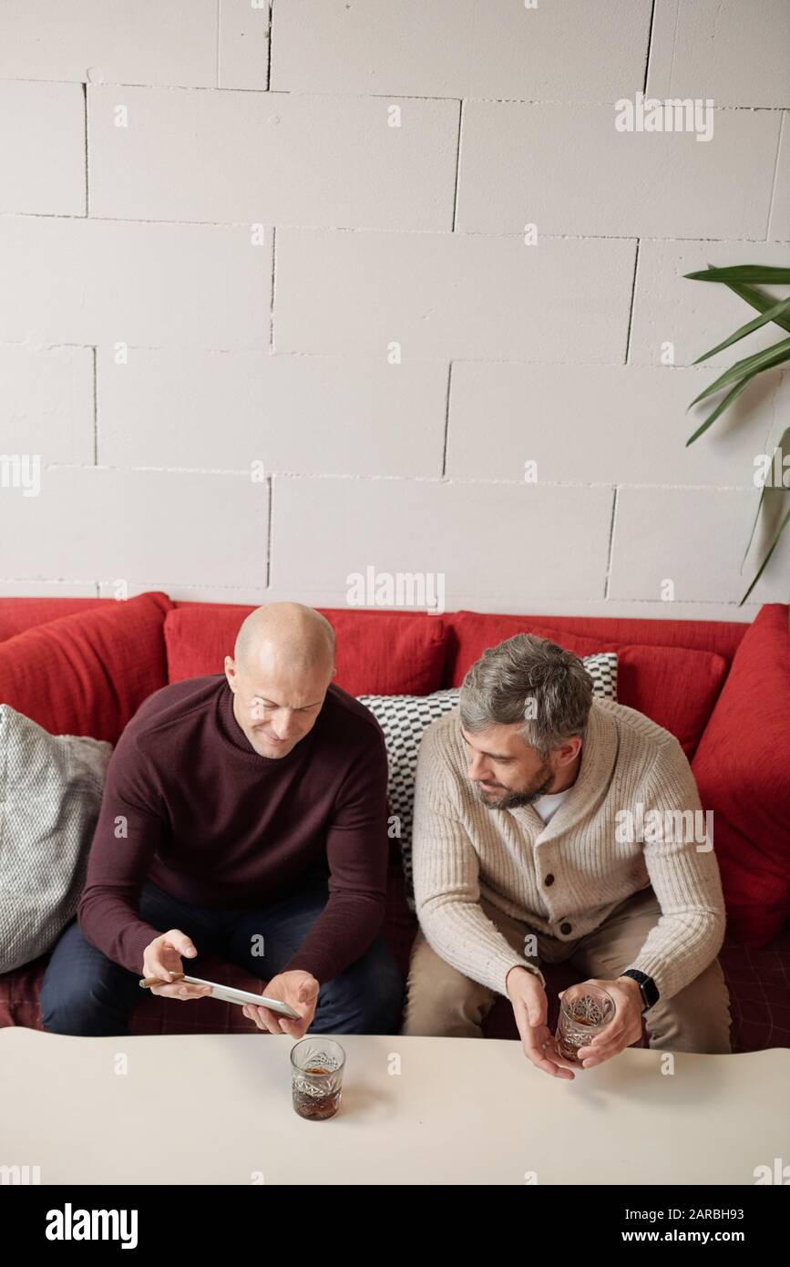 Männer teilen Nachrichten über Glas Whisky Stockfoto