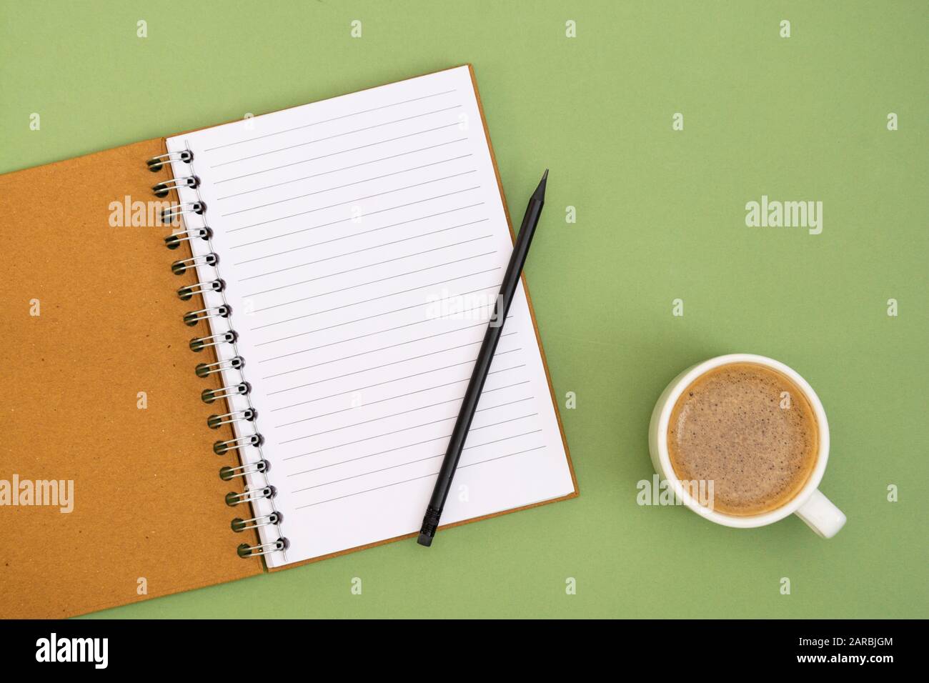 Öffnen Sie das Notebook mit leerer Seite und Kaffeetasse. Tischplatte, Arbeitsbereich auf grünem Hintergrund. Minimalistischer flacher Lay. Stockfoto