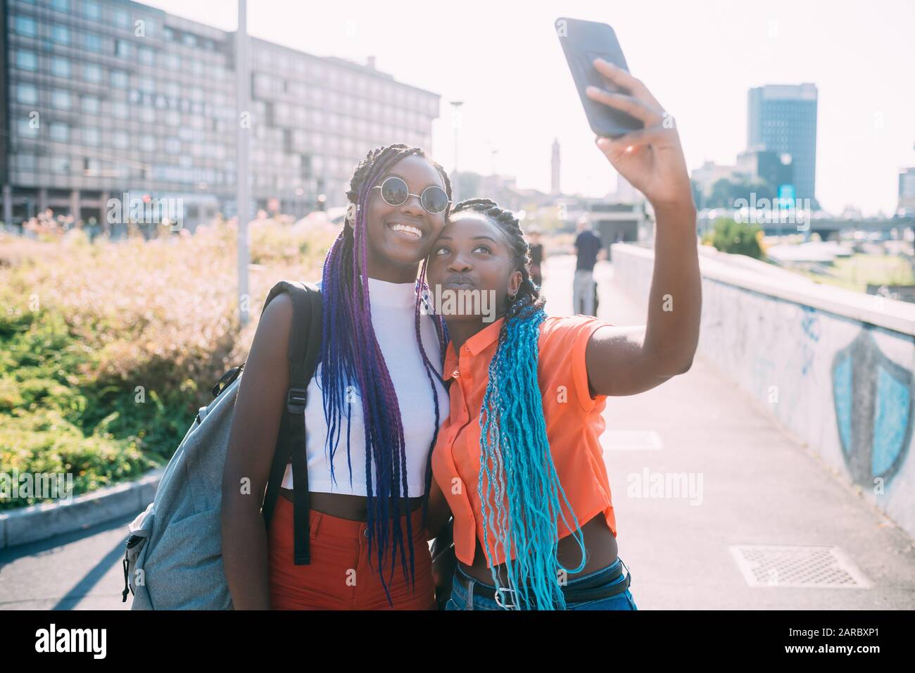 Junge schöne schwarze Schwestern Hintergrundbeleuchtung im Freien mit Smartphone, das selfie nutzt - gesellig, smombie, Technologiekonzept Stockfoto