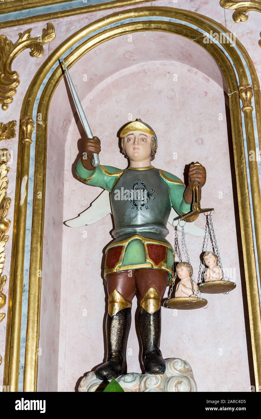 Statue der Person in Rüstung mit Flügeln, die Schwert hält und Babys auf einer Waage wiegt, Igreja Matriz de Alvor, katholische Kirche, Alvor, Algarve, Portugal Stockfoto