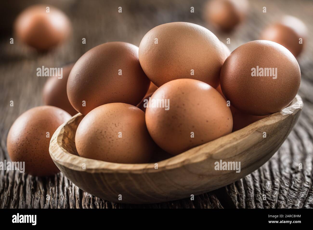 Frische rohe Eier in Holzschale auf rustikalem Holztisch Stockfoto