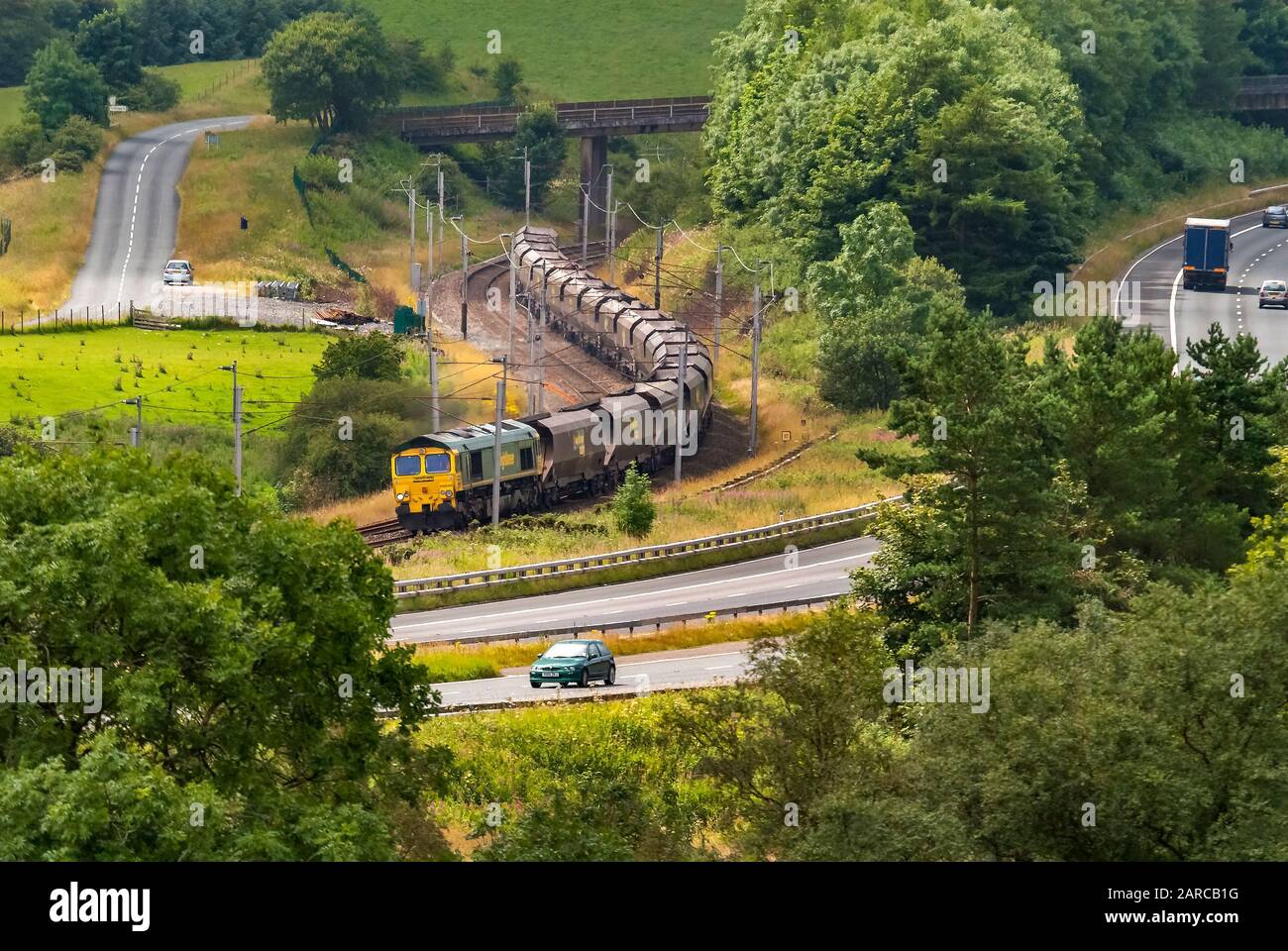 Die Hauptlaine an der Westküste am Beck Foot Cumbria. Eine Lok der Klasse 66, die Kohlekraftwagen in Richtung Norden transportiert. Die Old Scotch Road ist auf der linken Seite mit Th zu sehen Stockfoto