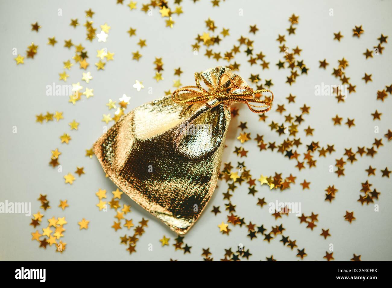 Goldener kleiner Beutel oder Beutel mit leuchtenden Konfetti- oder Glitzereffekt. Urlaubskonzept. Stockfoto