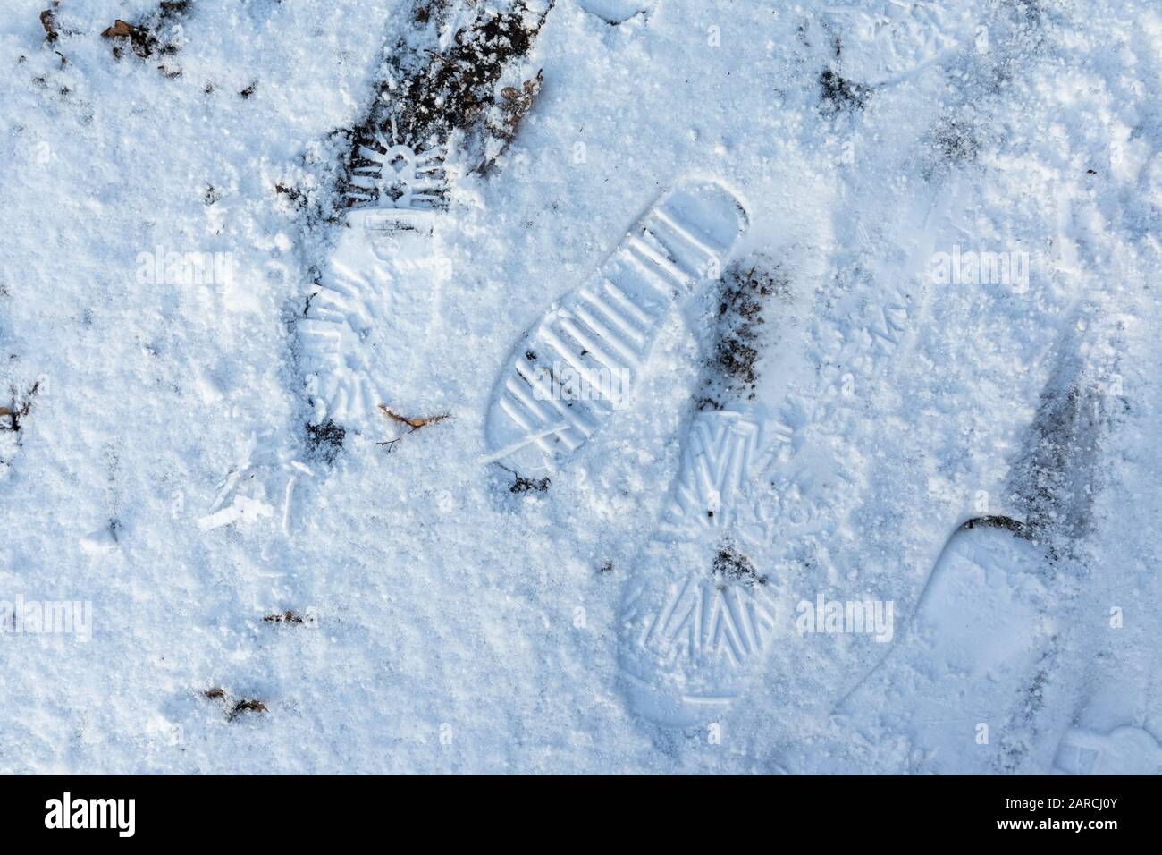 Fußabdrücke auf weißen Schnee Winter Natur drucken Nahgrund. Öko Umwelt menschliche Fußschuhe tragen Drucke an einem frischen, kühlen, sonnigen Tag Stockfoto