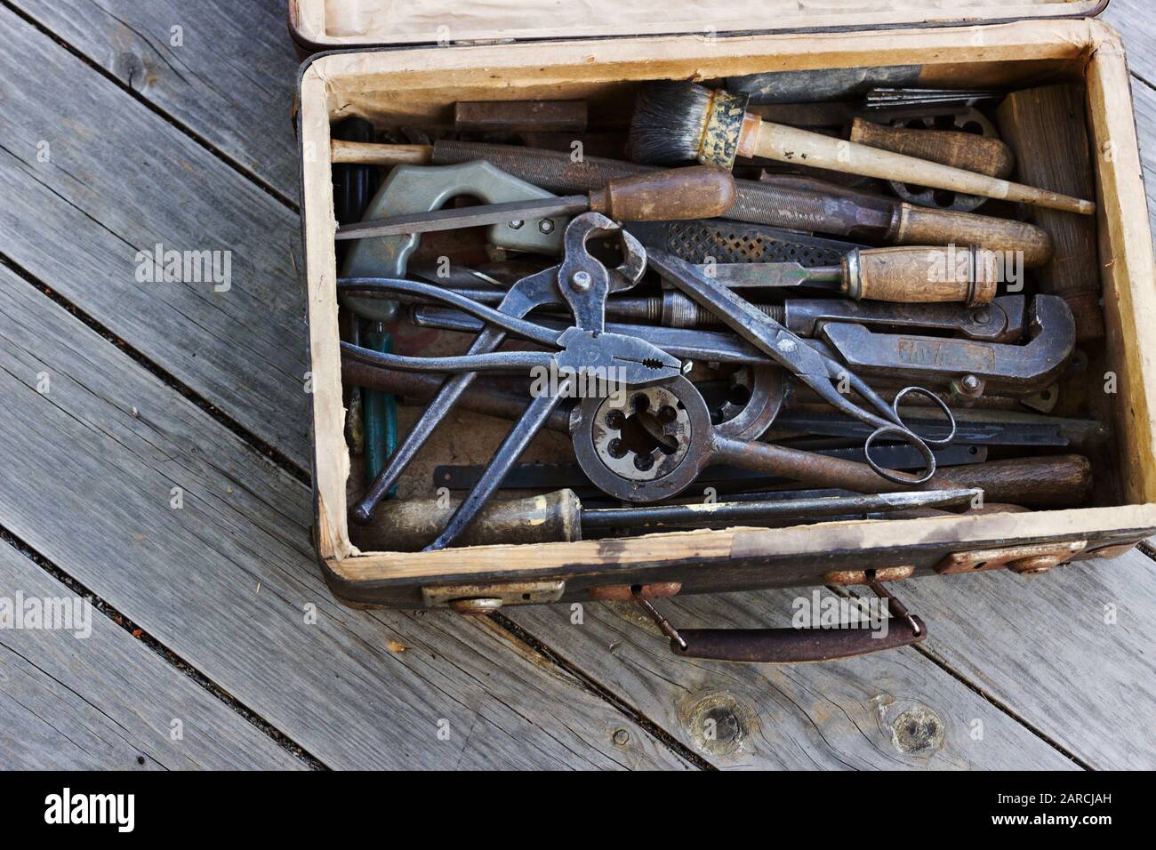 Alter Koffer mit den verschiedenen Handwerkzeugen auf den Holztafeln Stockfoto
