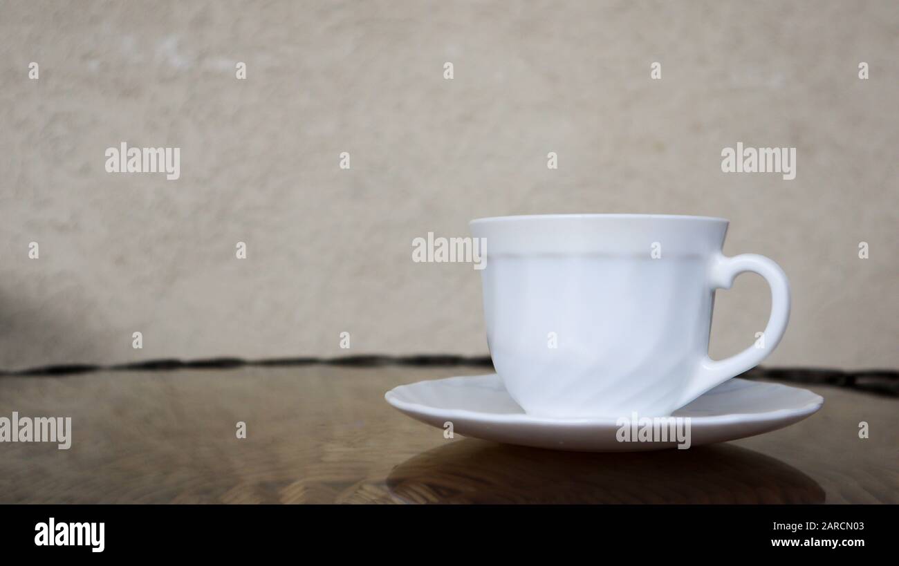 Heißer aromatischer Kaffee mit Milch. Frisch zubereitetes Getränk wird in einer modernen Tasse auf einem leichten Korbtisch serviert. Stockfoto
