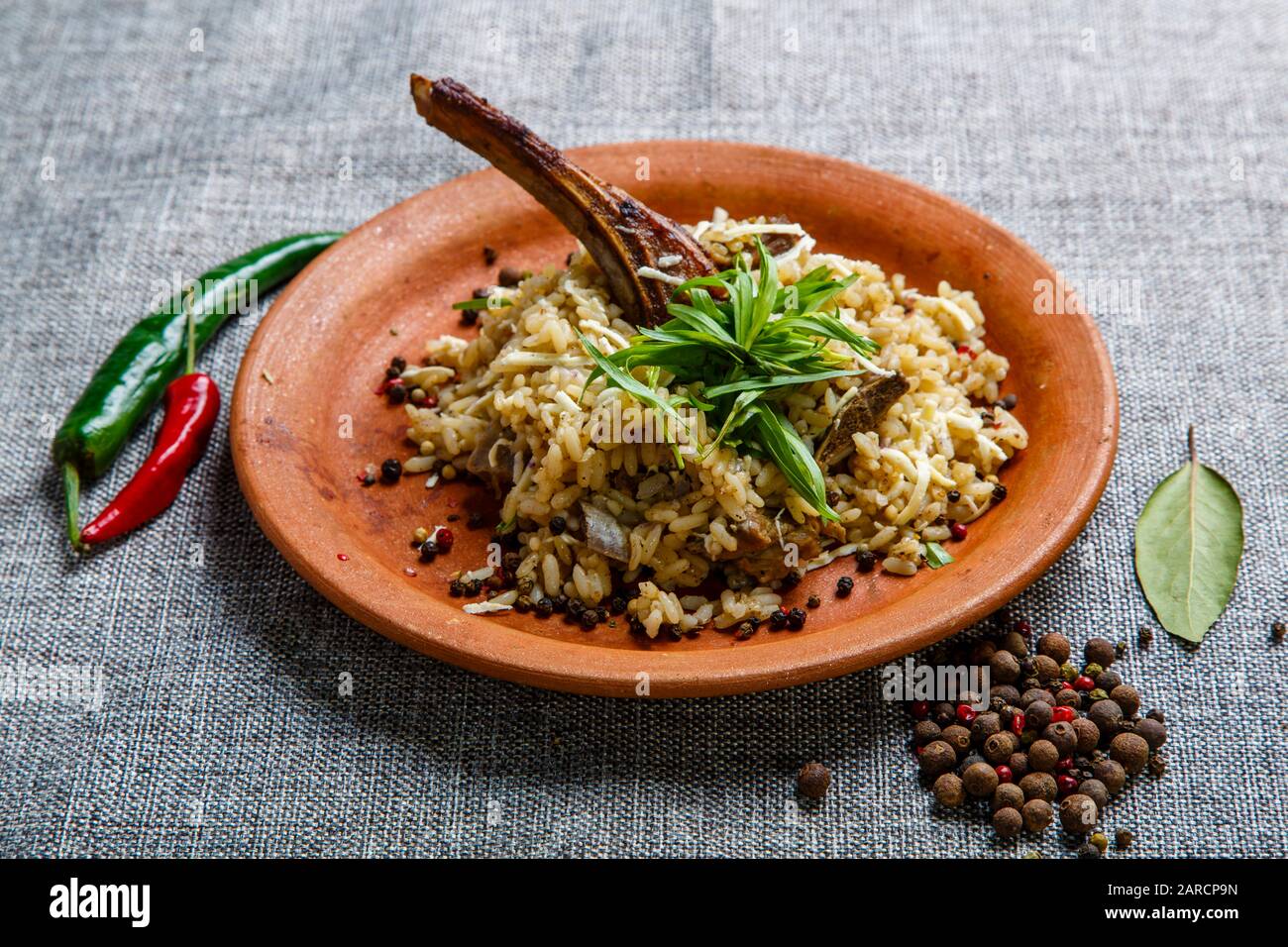 Lammrippe mit Reis auf einer Tonplatte. Strukturierte graue Leinwand. Stockfoto