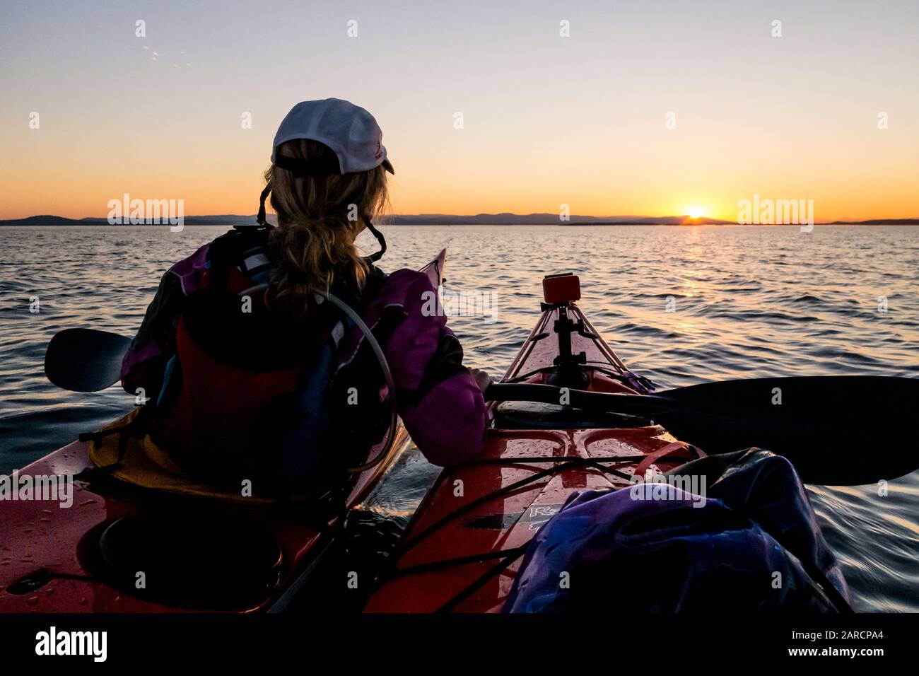 Die Kajakfahrer des Meeres beobachten den Sonnenuntergang, der über die Haro Strait nach Nordwesten in Richtung Vancouver Island, BC, Kanada blickt. Stockfoto
