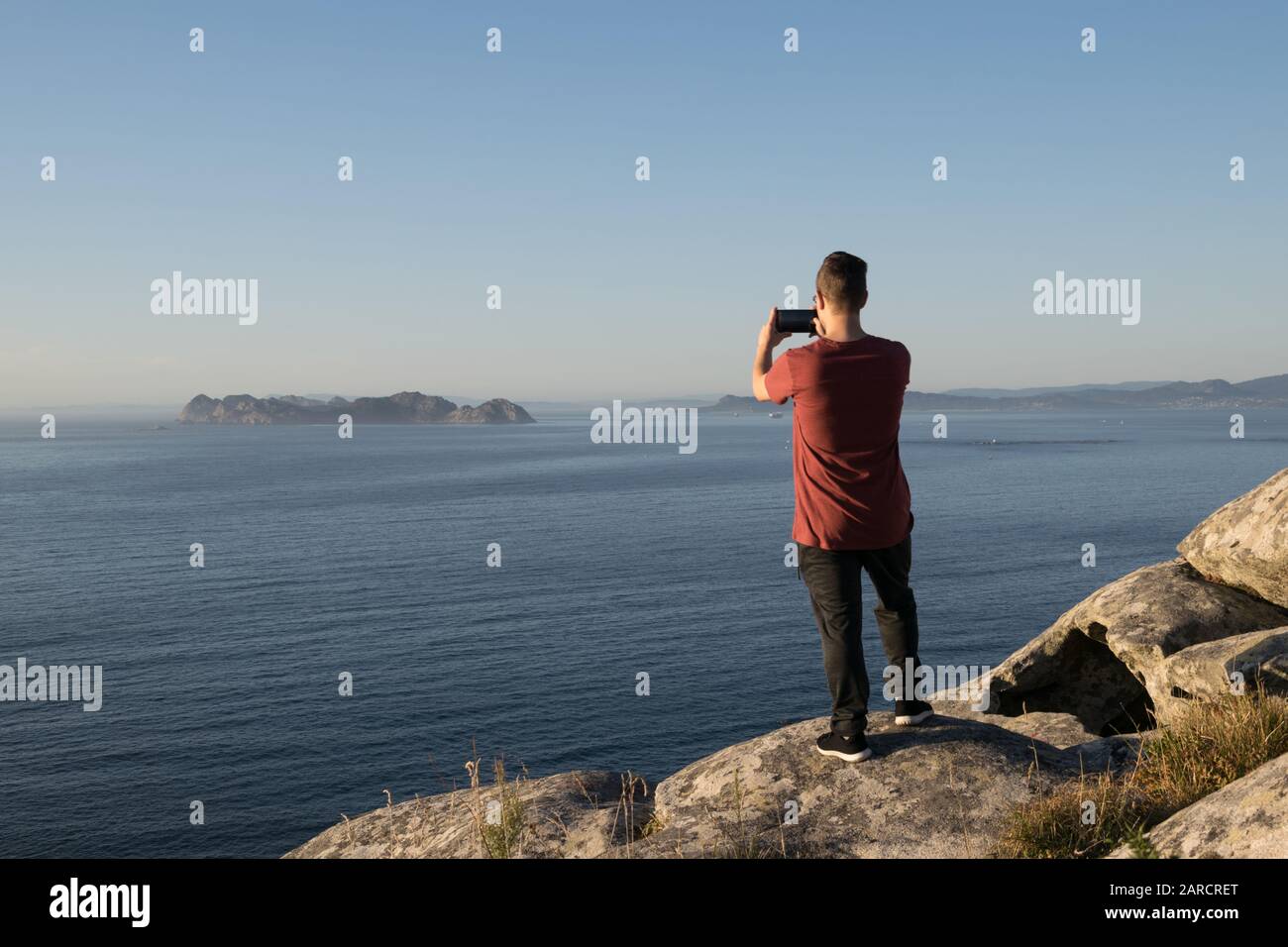 Rückansicht eines Jungen, der vom Berg ein Foto vom Meer gemacht hat Stockfoto