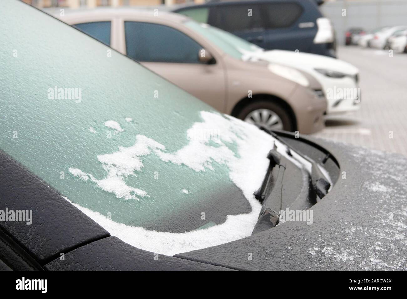 Windschutzscheibe in Eis und Schnee. Autos werden im Winter geparkt. Automatische Vereisung. Stockfoto