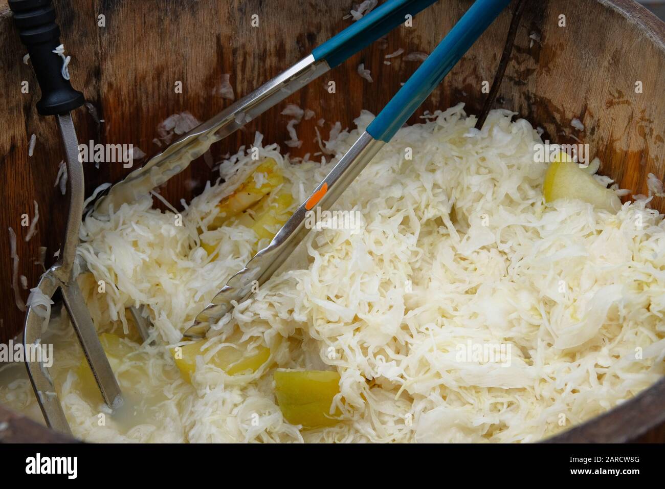 Sauerkraut mit Äpfeln in Holzfass wird auf dem lokalen Markt nach Gewicht verkauft. Fermentiert konserviertes vegetarisches Konzept für gesundes Essen. Stockfoto