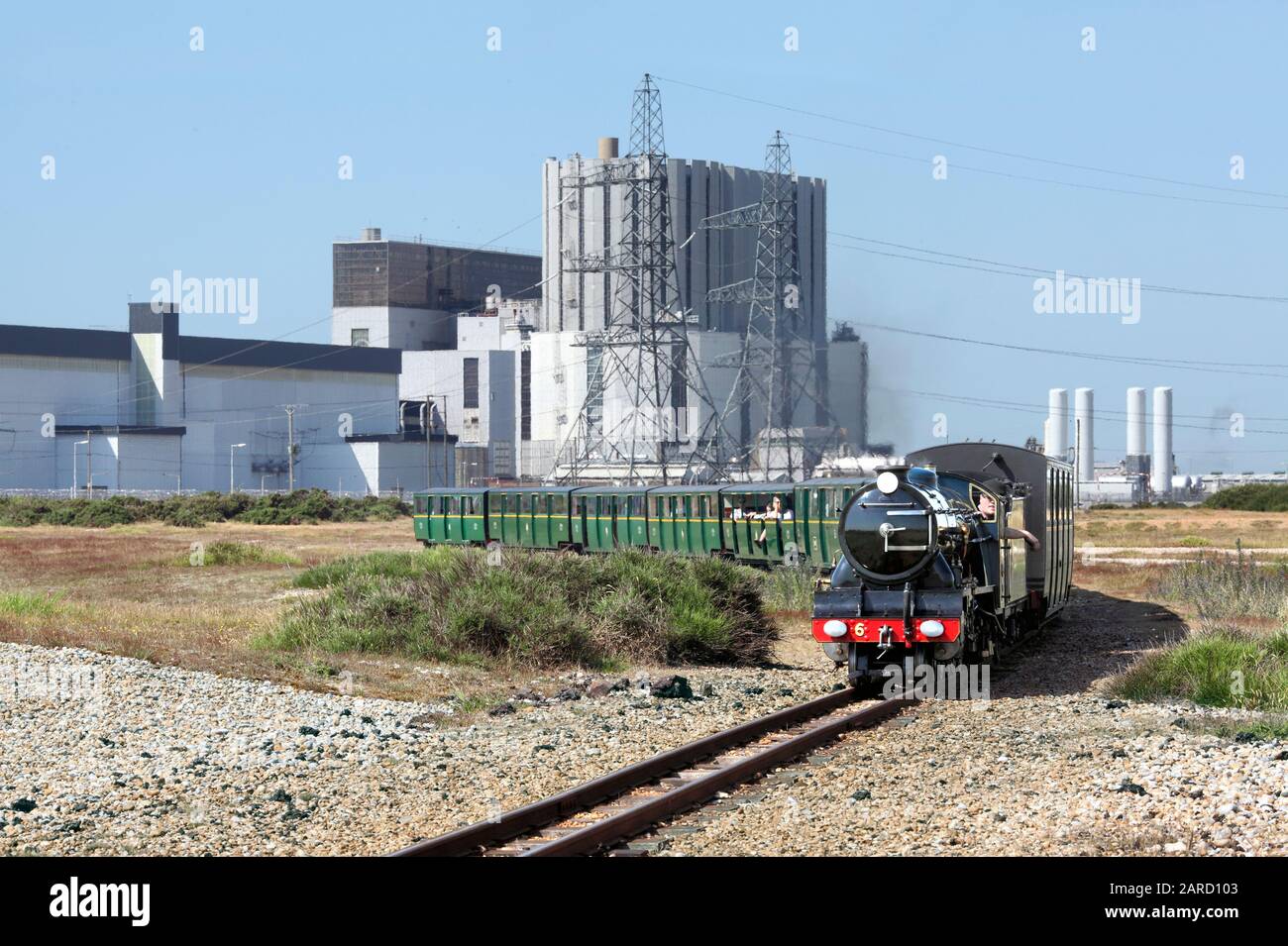 Ein Zug auf der schmalspurigen Romney, Hythe and Dymchurch Railway fährt östlich von Dungeness, im Hintergrund das Kernkraftwerk Dungeness B. Stockfoto