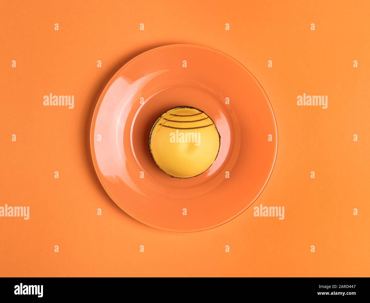 Gelber runder Kuchen auf dem orangefarbenen Tisch. Draufsicht Stockfoto