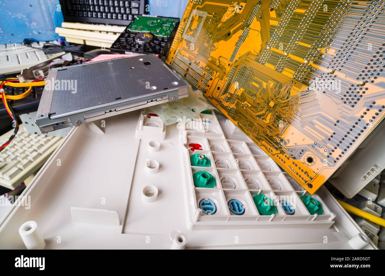 Zerlegte Computerhardteile. E-Waste Pfahldetails. Farbige Gummikuppelschalter auf der Tastatur. Leiterplatte auf Mainboard, Laptop-CD-Laufwerk, PC-Festplatte. Stockfoto