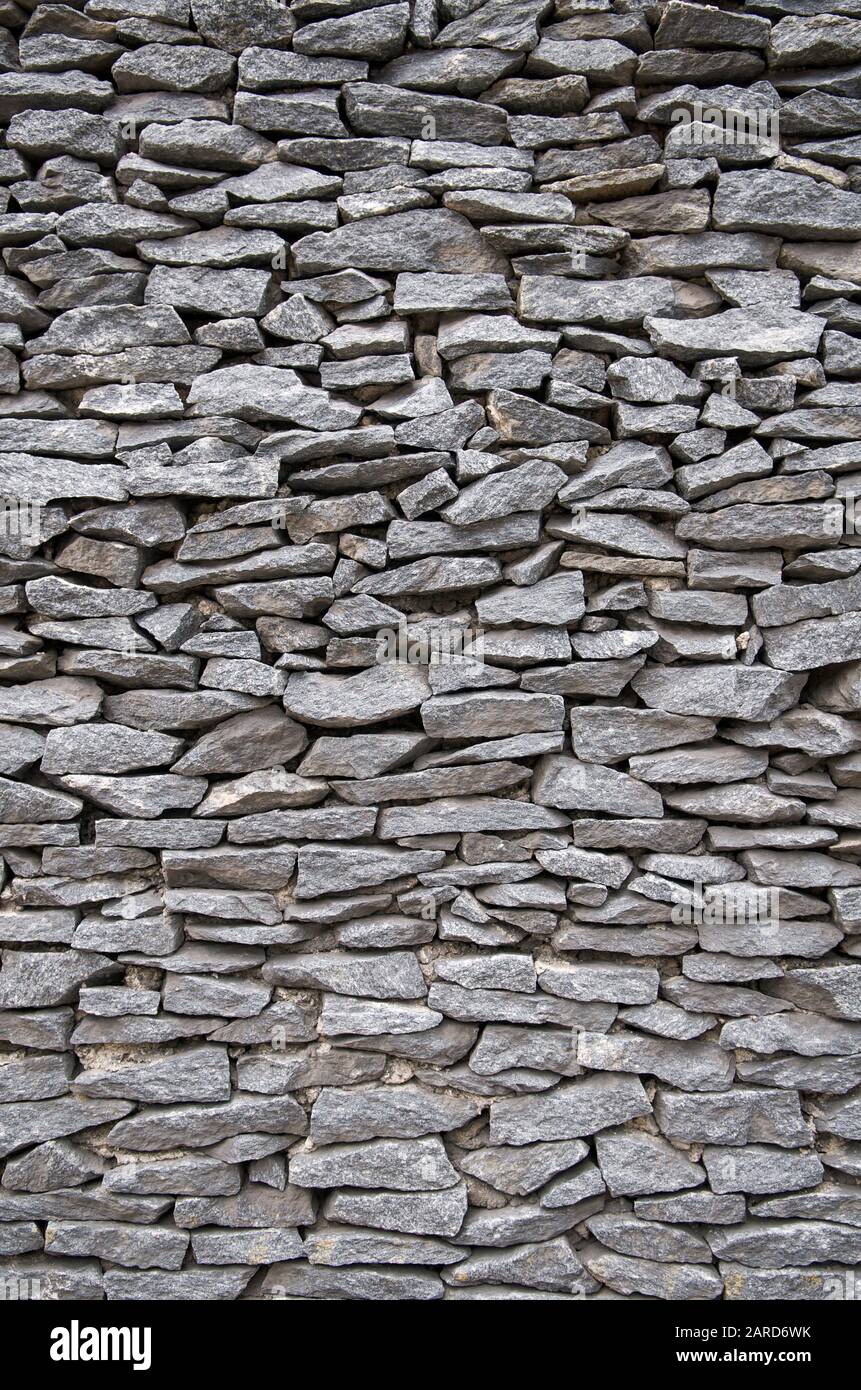 Vertikale Nahaufnahme von flachen grauen Steinen, die eng in einer Wand gestapelt sind Stockfoto