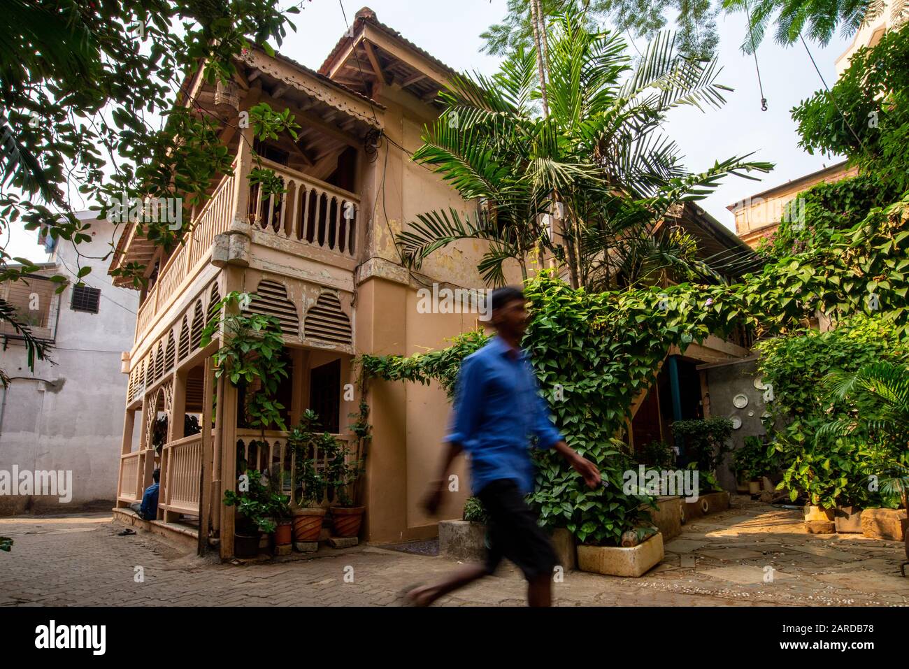 Ein historisches Holzhaus in einem alten Viertel von Mumbai mit einem nicht erkennbaren Mann, der an Indien vorbeigeht Stockfoto