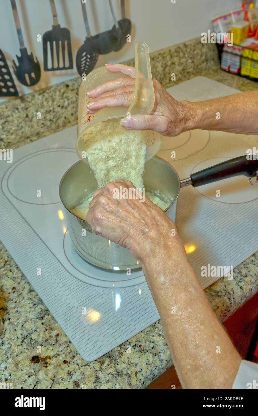 Einige vorher gemessene Instantkartoffeln werden in einen Kochtopf gegossen. Stockfoto