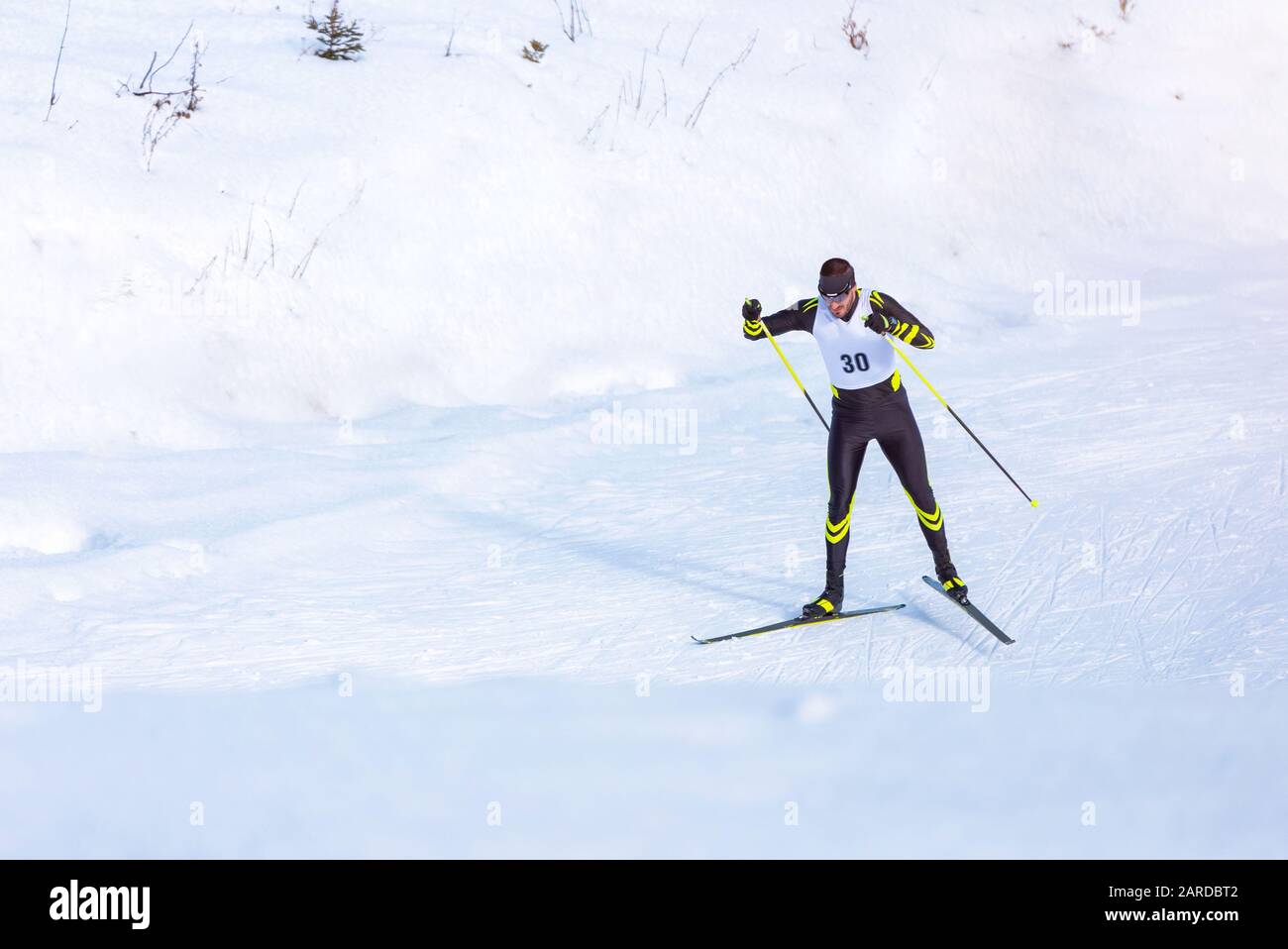 Ein Mann Skilangläufer auf der Strecke. Kerl mit moderner Skiausrüstung und Rennnummer Stockfoto