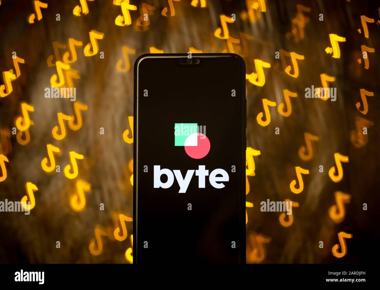 Byte App-Logo auf Smartphone und Bokeh in Form des TikTok Logos im Hintergrund. Keine Montage. Keine Fotobearbeitung. Es wird eine benutzerdefinierte Bokeh-Shape-Technik verwendet. Stockfoto