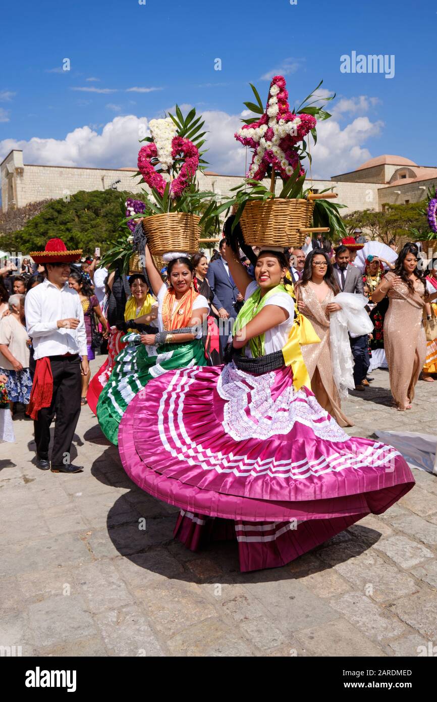 Frau tanzt in fließenden traditionellen Outfit mit Blumenkorb Teil der traditionellen Paradiese die Straßen von Oaxaca. Stockfoto