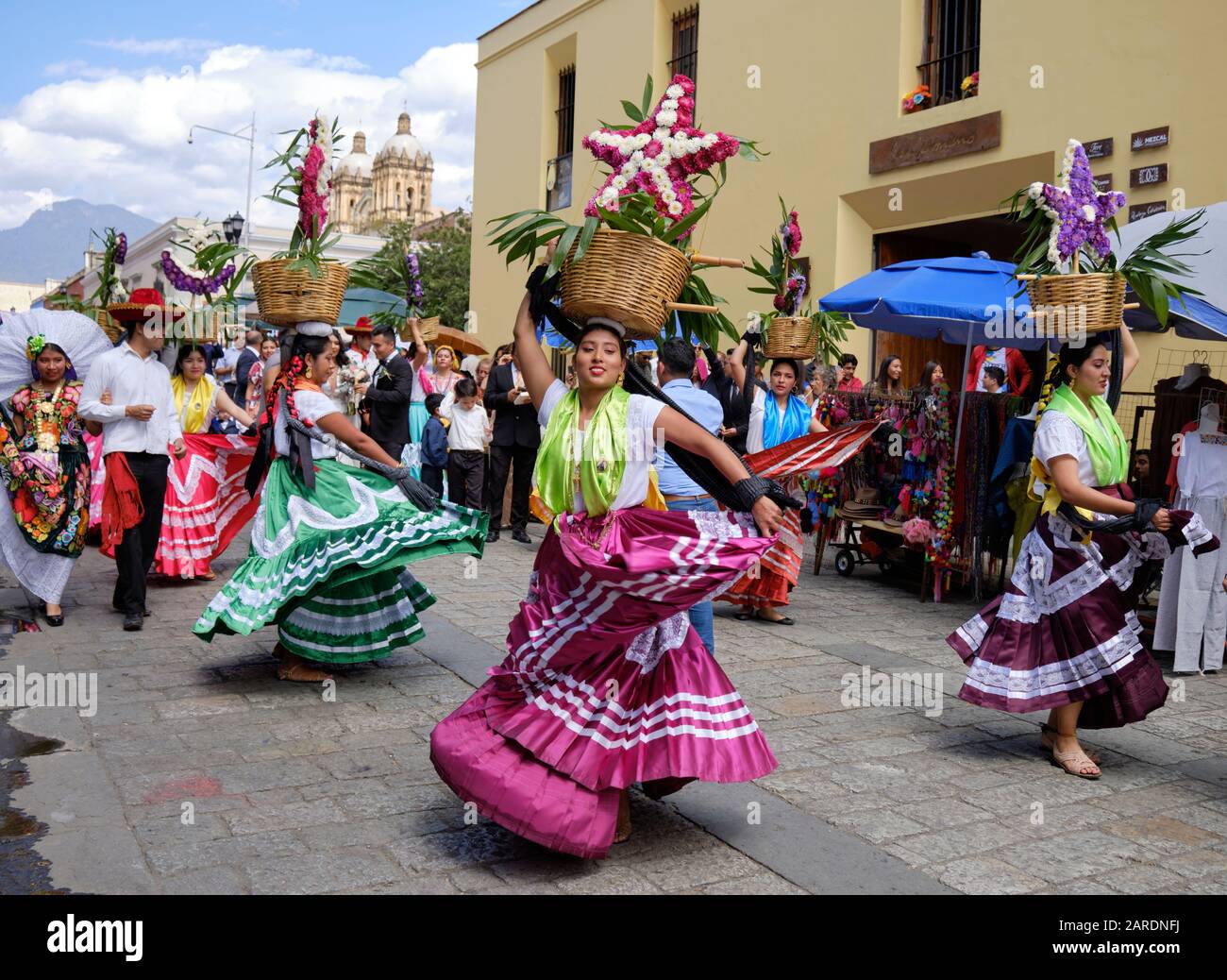 Frau tanzt in fließenden traditionellen Outfit mit Blumenkorb Teil der traditionellen Parade auf den Straßen von Oaxaca. Stockfoto